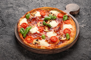 Wooden board with tasty pizza on dark grey background
