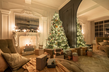 Christmas evening in the light of candles and garlands. Classic luxurious apartments with decorated christmas tree and presents. Living with fireplace, columns and stucco.