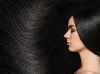 Portrait of beautiful young woman with healthy long hair on grey background