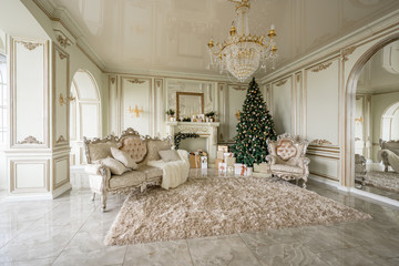 Christmas morning. Classic luxurious apartments with decorated christmas tree and presents. Living with fireplace, columns and stucco.