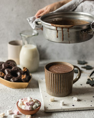 Cup of hot chocolate poured on bright background with cookies and marshmllow