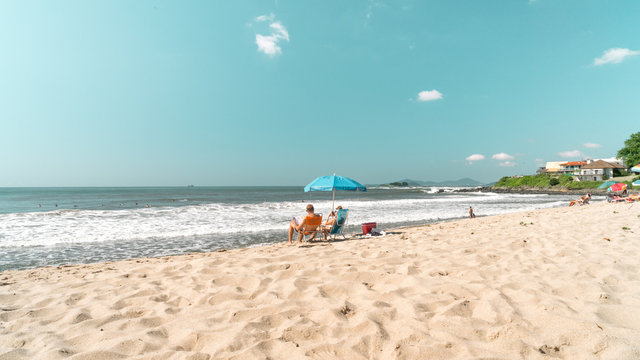 Um belo dia de praia com c&eacute;u azul areia clara e guarda sol com cadeiras
