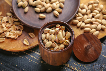 Jar with tasty pistachio nuts on table