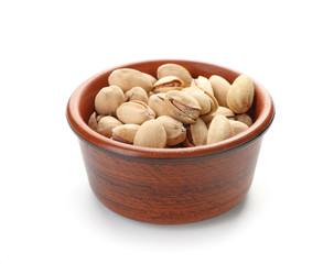Bowl with tasty pistachio nuts on white background