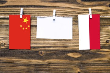 Hanging flags of China and Indonesia attached to rope with clothes pins with copy space on white note paper on wooden background.Diplomatic relations between countries.