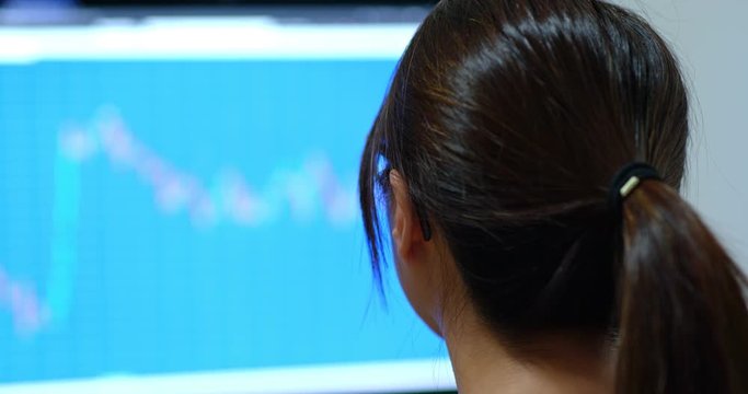 Woman look at computer screen with stock market data graph