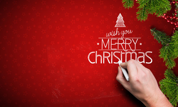 hand writing a Merry Christmas message on red background