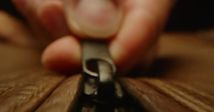 Close up of zipping up a leather jacket, macro shot of zipper on brown leather bag, everyday task, dramatic look, red epic