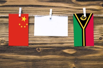 Hanging flags of China and Vanuatu attached to rope with clothes pins with copy space on white note...