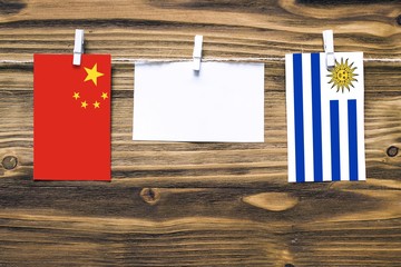 Hanging flags of China and Uruguay attached to rope with clothes pins with copy space on white note...