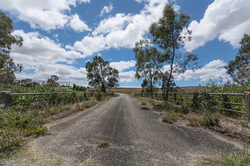 Old road bridge over grown, rural road landscape Australia.