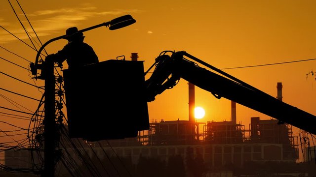Silhouette of an electrician to repair street lighting with sunset time lapse