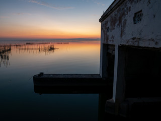  Salty lake hut and reflections in the water at sunset with orange colors in the Valencia lagoon