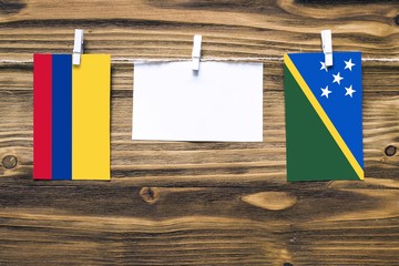 Hanging flags of Colombia and Solomon Islands attached to rope with clothes pins with copy space on...
