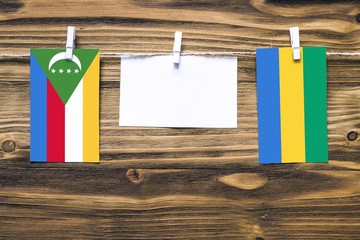 Hanging flags of Comoros and Gabon attached to rope with clothes pins with copy space on white note...