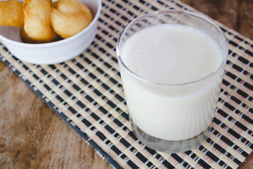 Soy milk in a glass and cup of fried cassava flour Resting on a brown wooden table