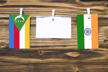 Hanging flags of Comoros and India attached to rope with clothes pins with copy space on white note...