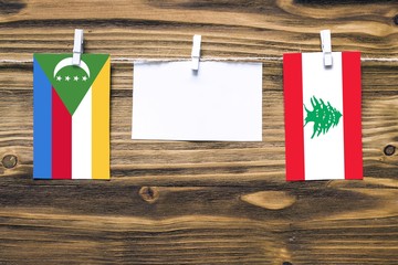 Hanging flags of Comoros and Lebanon attached to rope with clothes pins with copy space on white...