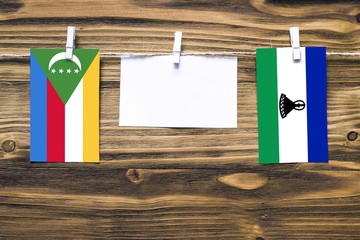 Hanging flags of Comoros and Lesotho attached to rope with clothes pins with copy space on white...