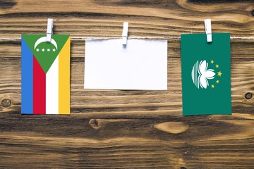 Hanging flags of Comoros and Macao attached to rope with clothes pins with copy space on white note...