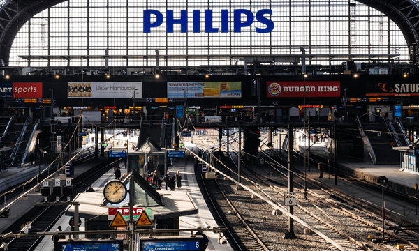 HAMBURG, GERMANY - MAR 20, 2018: Hamburg Hauptbahnhof wide interior with elevate view of trains, people traveling and huge Philips advertisement