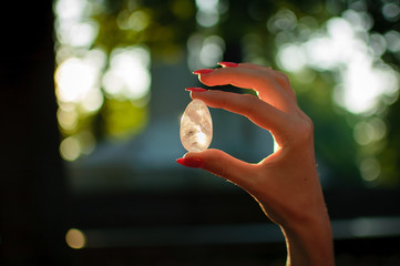 Female hand with transparent amethyst quartz yoni egg for vumfit, imbuilding or meditation. Shining...