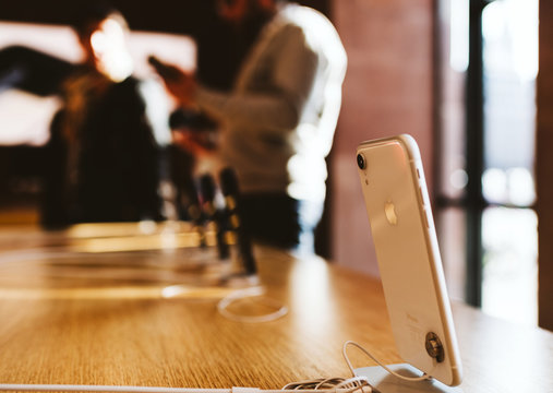 PARIS, FRANCE - OCT 26, 2018: Latest White IPhone XR Smartphone In Apple Store Computers During The Launch Day With Customer In Background