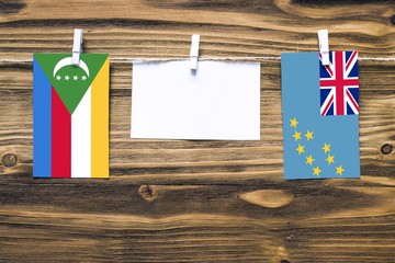 Hanging flags of Comoros and Tuvalu attached to rope with clothes pins with copy space on white...