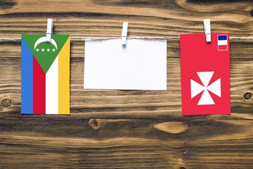 Hanging flags of Comoros and Wallis And Futuna attached to rope with clothes pins with copy space...