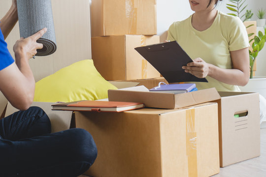 Couple checking list of stuff before pack to boxes prepare for relocation to new home.