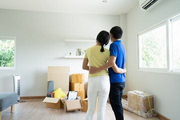 Fototapeta na wymiar Start your new family in new house. Asian couple hugging together and looking at room in new house with many stuff on the floor after moving in.