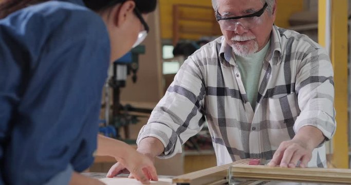 Two carpenter working together at workshop. They trying to make wood furniture at workshop.