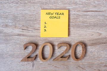 Naklejka premium 2020 Happy New years Goal on yellow paper note and wooden number on table for copy space. New Start, Resolution, Goals and Mission Concept