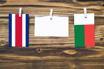 Hanging flags of Costa Rica and Madagascar attached to rope with clothes pins with copy space on white note paper on wooden background.Diplomatic relations between countries.