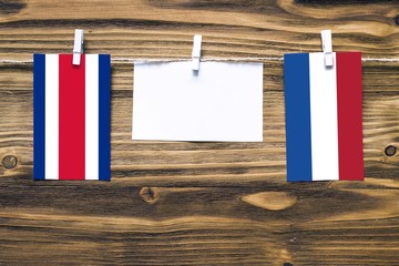 Hanging flags of Costa Rica and Netherlands attached to rope with clothes pins with copy space on white note paper on wooden background.Diplomatic relations between countries.