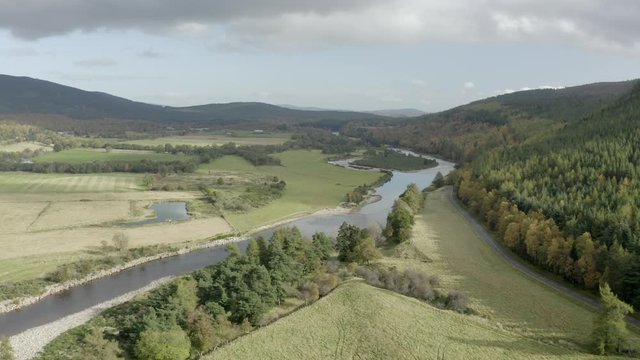 Aerial view of the River Dee near the Scottish town of Ballater in the Cairngorms National Park, Aberdeenshire. Flying forward over fields and the river with zoom in.