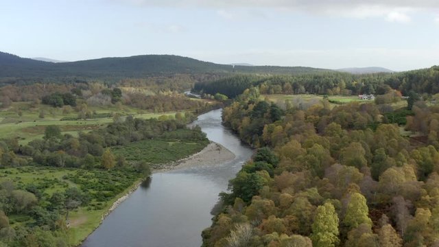 Aerial view of the River Dee near the Scottish town of Ballater in the Cairngorms National Park, Aberdeenshire. Elevating view above the river and autumn trees with zoom in.