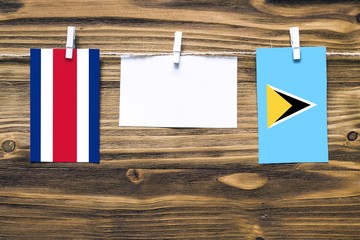 Hanging flags of Costa Rica and Saint Lucia attached to rope with clothes pins with copy space on...
