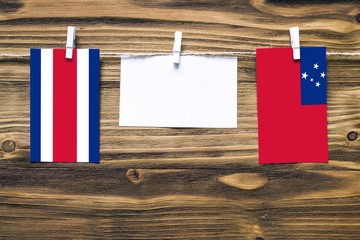 Hanging flags of Costa Rica and Samoa attached to rope with clothes pins with copy space on white...