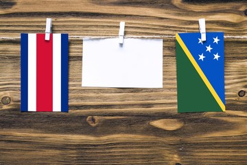 Hanging flags of Costa Rica and Solomon Islands attached to rope with clothes pins with copy space...