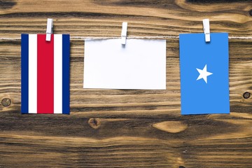 Hanging flags of Costa Rica and Somalia attached to rope with clothes pins with copy space on white...