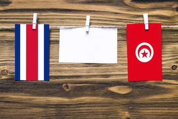 Hanging flags of Costa Rica and Tunisia attached to rope with clothes pins with copy space on white...