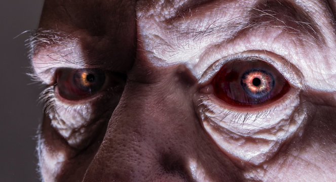 Close-up of the creepy eyes of an elderly man. Concept: Halloween