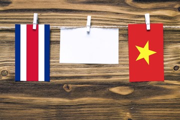 Hanging flags of Costa Rica and Vietnam attached to rope with clothes pins with copy space on white note paper on wooden background.Diplomatic relations between countries.