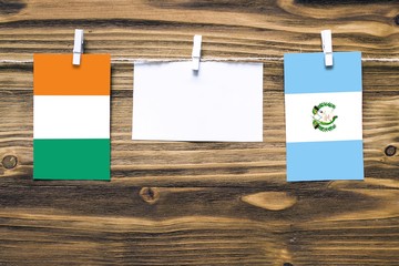 Hanging flags of Cote D'Ivoire and Guatemala attached to rope with clothes pins with copy space on...