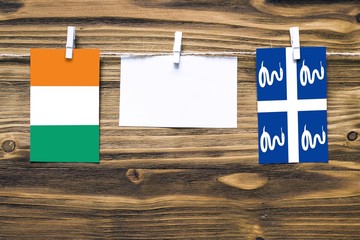 Hanging flags of Cote D'Ivoire and Martinique attached to rope with clothes pins with copy space on...