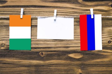 Hanging flags of Cote D'Ivoire and Russia attached to rope with clothes pins with copy space on...