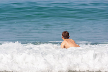 A child sitting in the sea foam