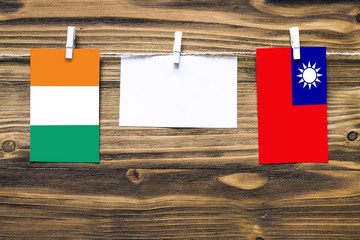 Hanging flags of Cote D'Ivoire and Taiwan attached to rope with clothes pins with copy space on...