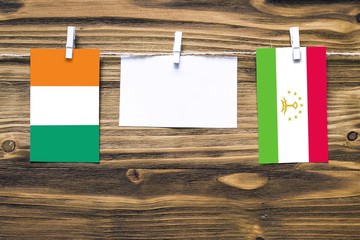 Hanging flags of Cote D'Ivoire and Tajikistan attached to rope with clothes pins with copy space on...